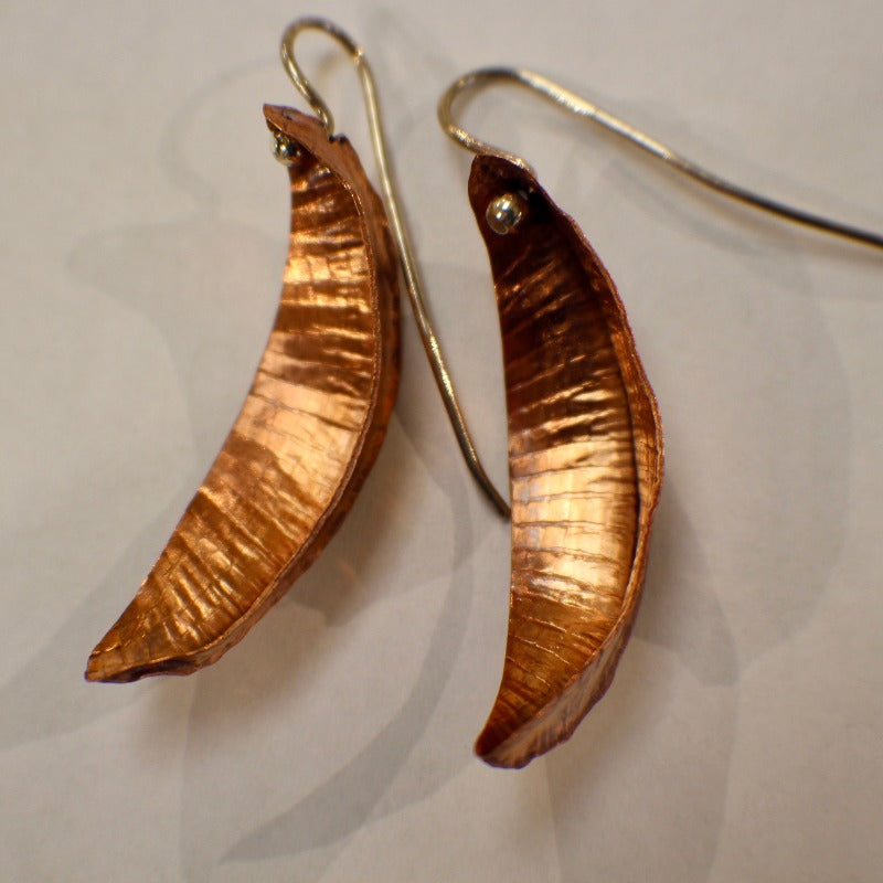 Pair of copper leaf-shaped earrings, convex like seed pods