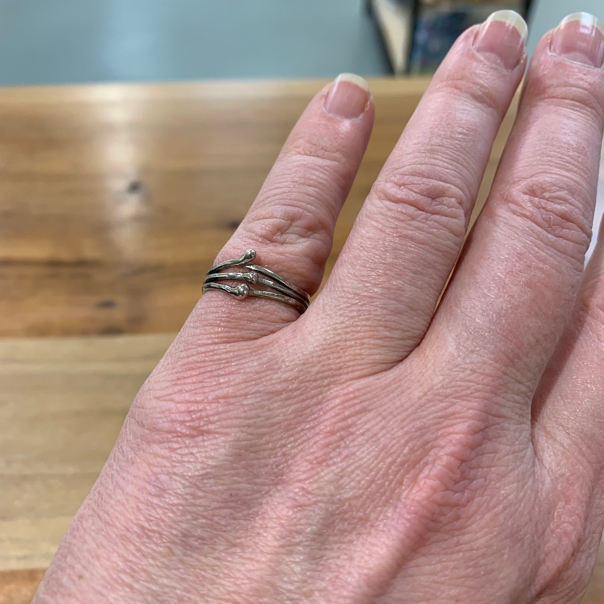 Woman wearing sterling silver pinkie ring, three twisted strands with silver balls