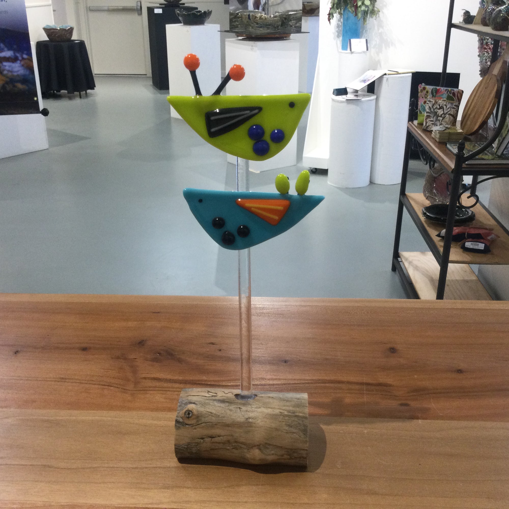 Glass scuplture of two stylized birds on wooden base.