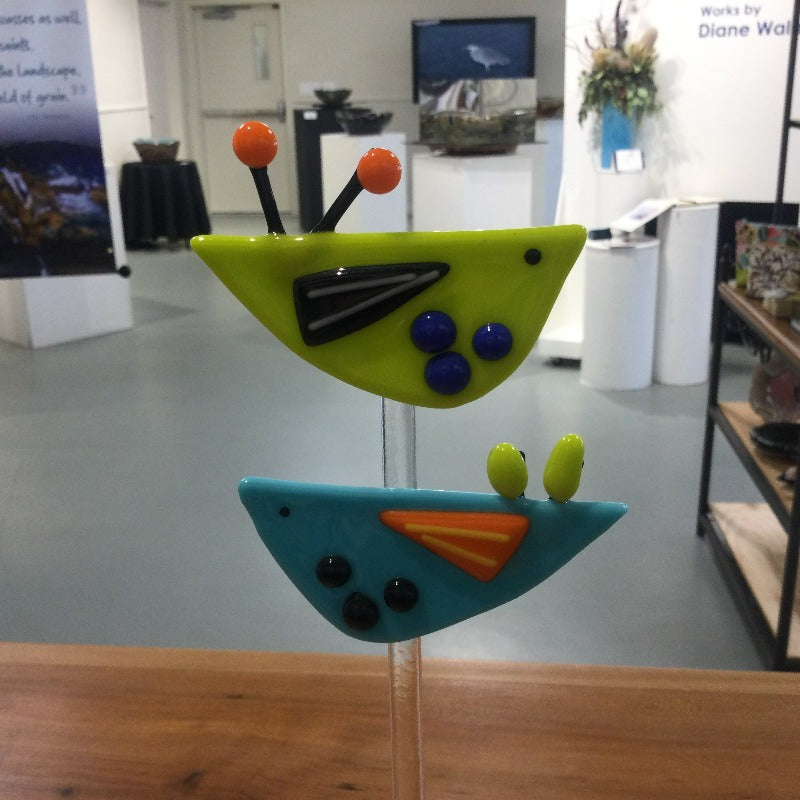 Glass scuplture of two stylized birds on wooden base.