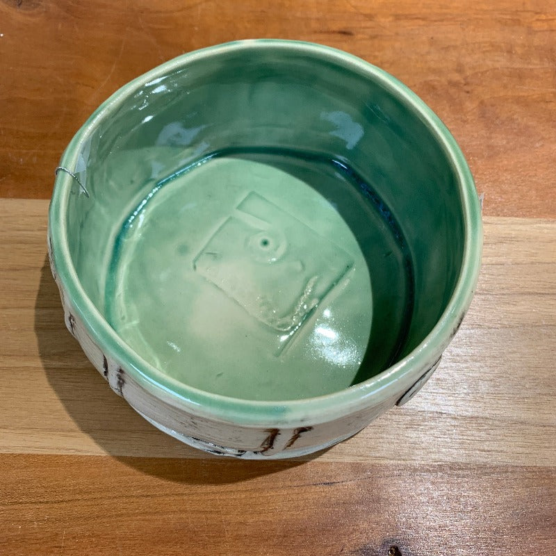 Interior of clay bowl, light green with abstract shape on bottom