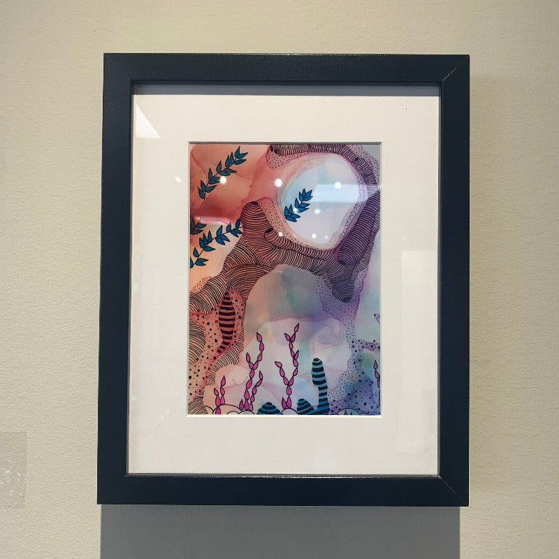 Black framed print of whimsical alcohol ink and black ink drawing in variety of colours.