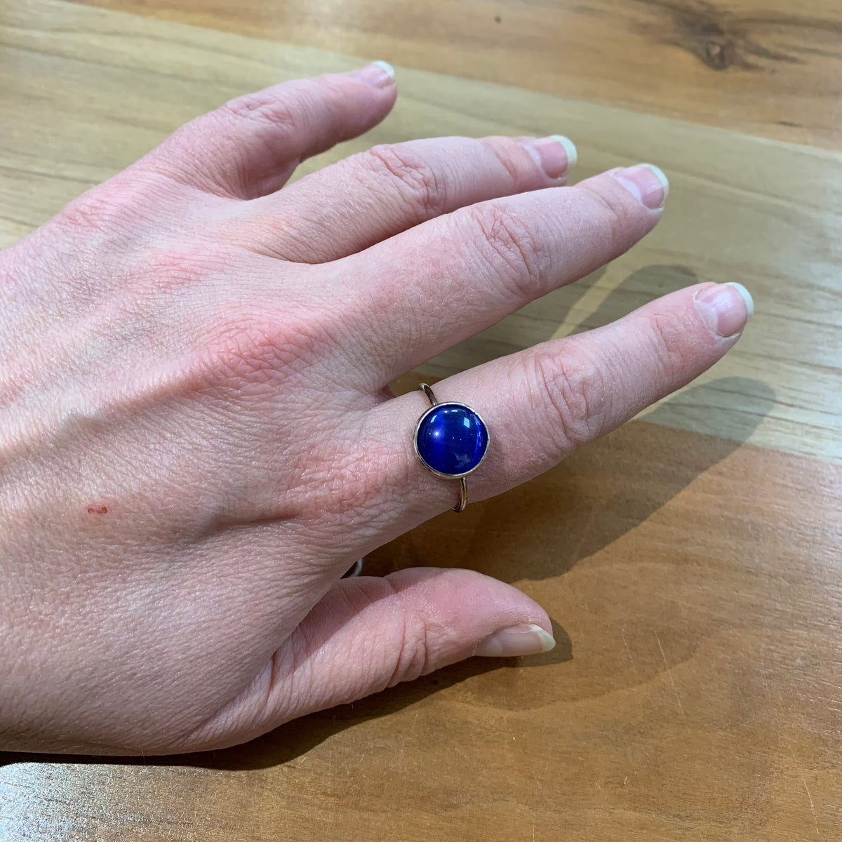 Woman wearing ring with large blue round stone