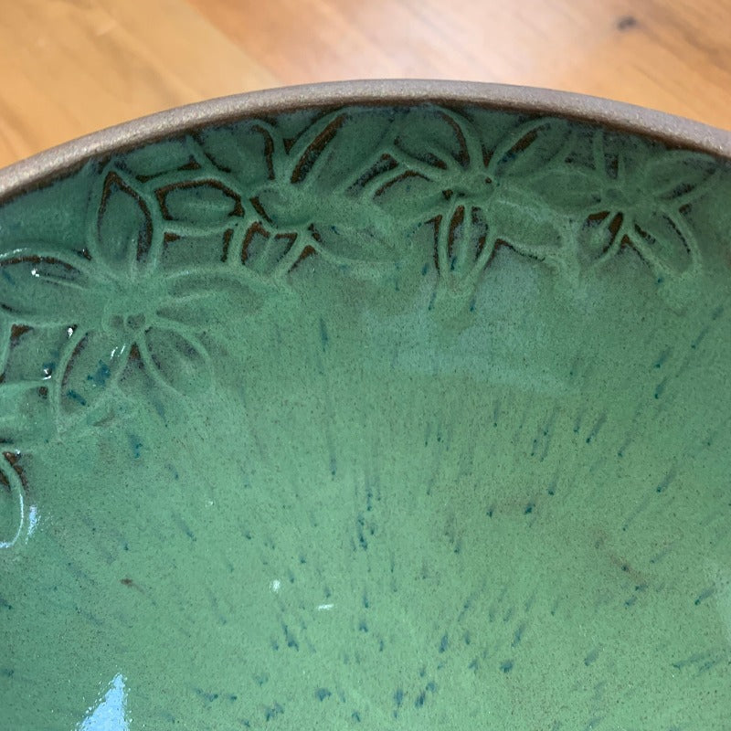 Detail of flowers on interior of clay bowl with green glaze